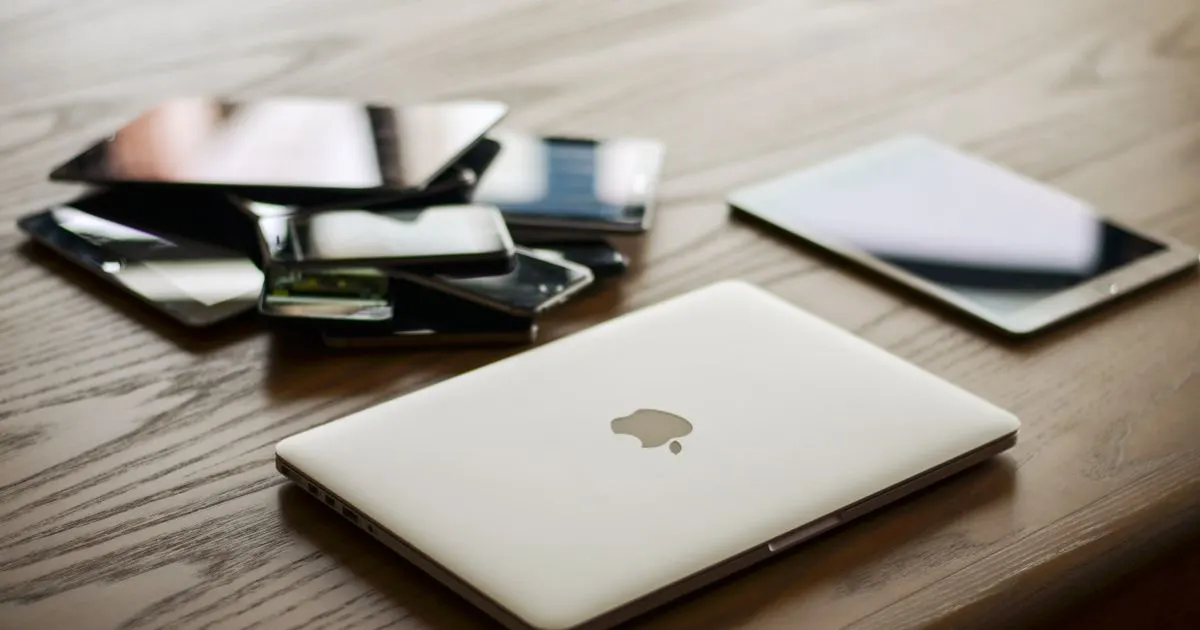 A laptop, tablet and phones on a desk